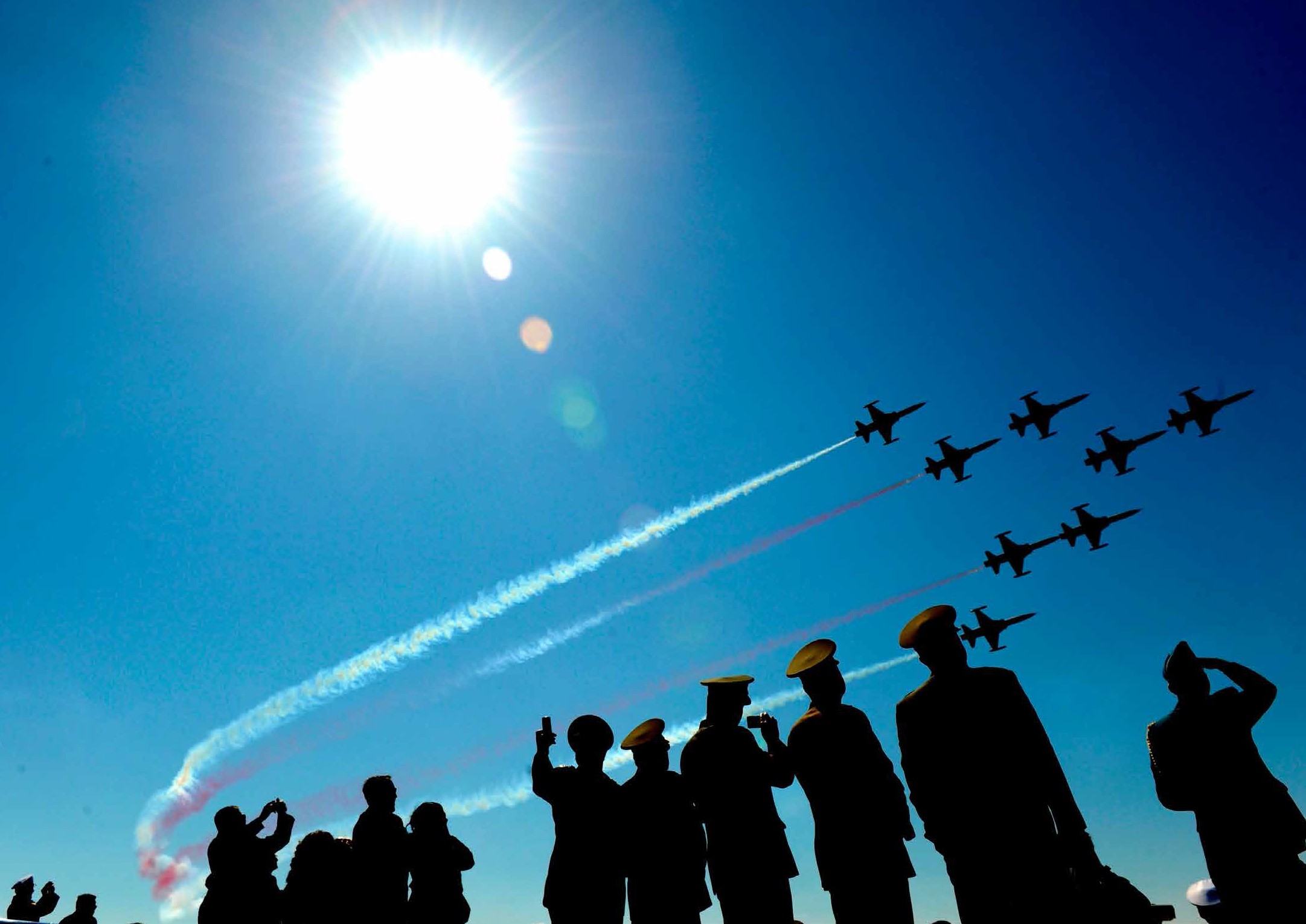 soldiers looking up at a jet formation in the sky